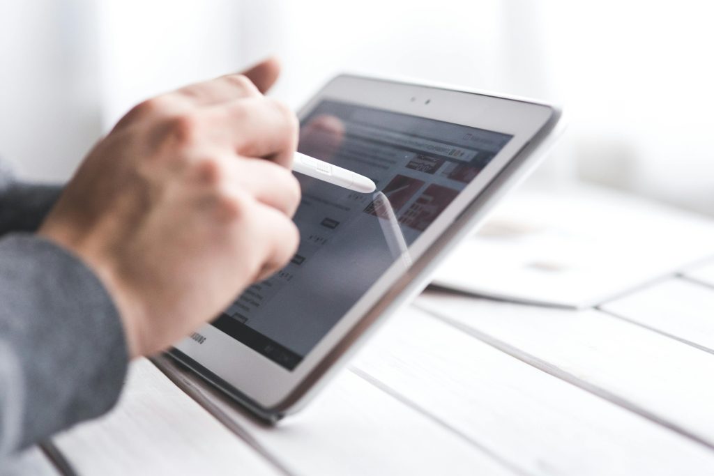 Close-up of a hand using a stylus on a tablet, showcasing digital technology interaction.